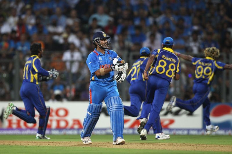 Sri Lankan cricketers celebrate as Sachin Tendulkar walks back to the pavilion after getting out