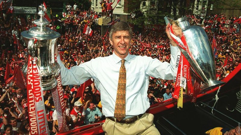 Arsene Wenger holding the Premier League and FA Cup
