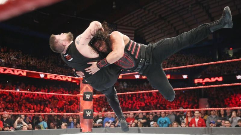 Roman Reigns delivering a spear to Kevin Owens
