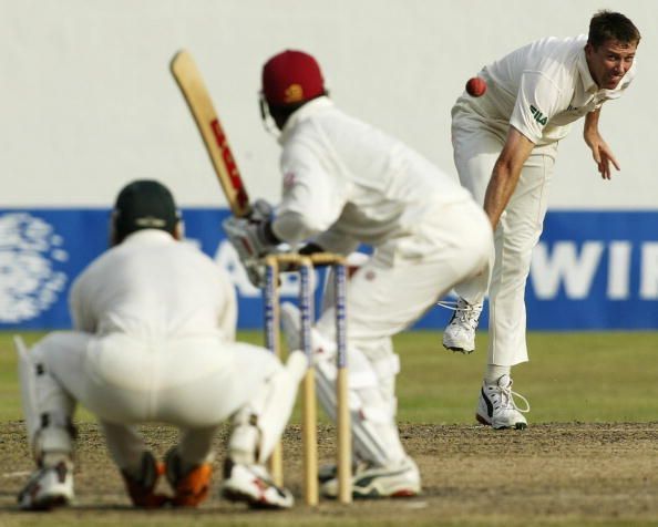 Adam Gilchrist of Australia stands up to the stumps as team mate Glenn McGrath bowls