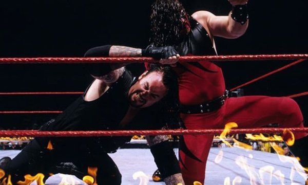Kane tries to burn his older brother in the ringside flames.