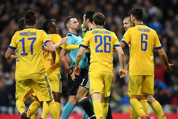 Juventus players confront referee Michael Oliver