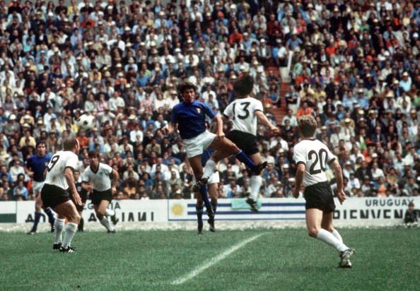 1970 World Cup Semi-Final, Mexico City, Mexico 17th June, 1970. Italy 4 v West Germany 3. West German player Gerd Muller jumps for the ball with an Italian defender as teammates Uwe Seeler (9) and Jurgen Grabowski (20) look on during the two teams&#039; semi-