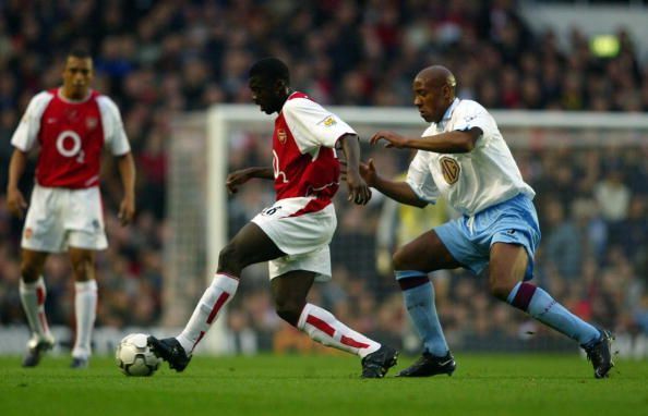 Dion Dublin of Aston Villa tries to tackle Kolo Toure of Arsenal