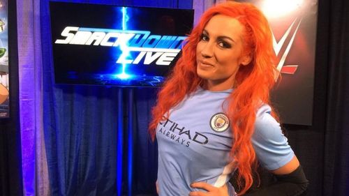 Becky Lynch wearing Manchester City's jersey.