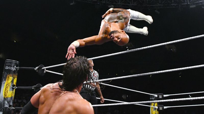 Ricochet sails over the top rope with a corkscrew plancha onto a hapless Adam Cole.