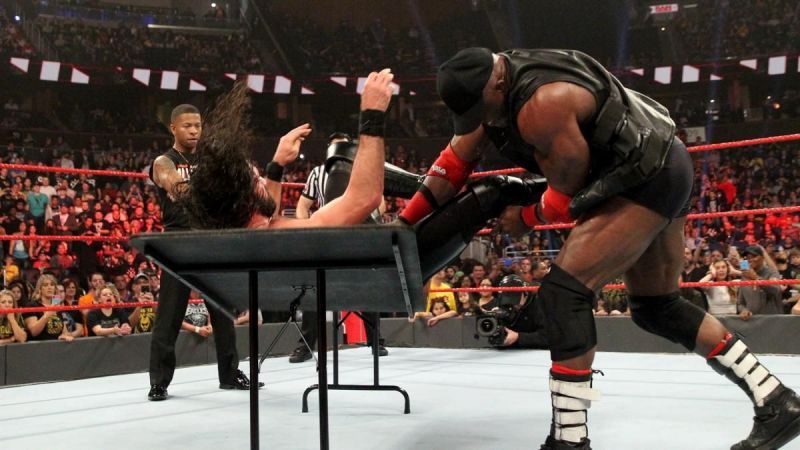 Lashley drives Rollins through the table...