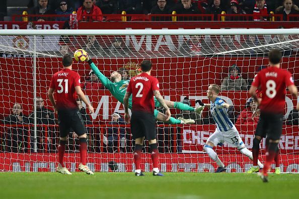 De Gea makes a save during a Huddersfield Town match, as Matic and Lindelof look on.