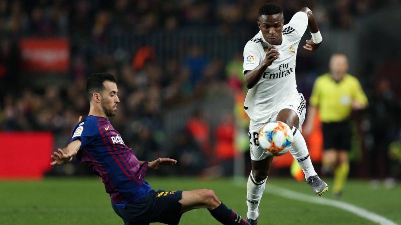 Vinicius Junior competes for the ball with Sergio Busquets