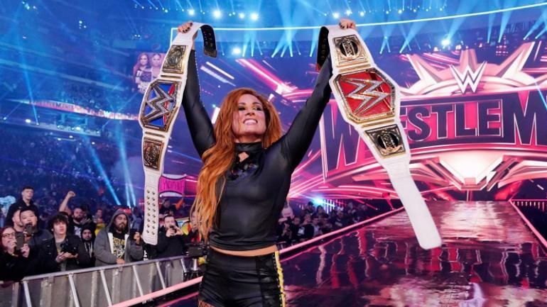 Becky Lynch proudly hefts both the Raw and Smackdown women&#039;s championships.
