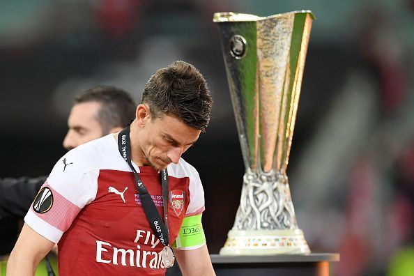 Koscielny walks past the Europa League trophy after Chelsea&#039;s 4-1 win over the Gunners late last month