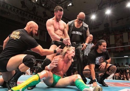 The Bullet Club pose with Kenny Omega's prone body