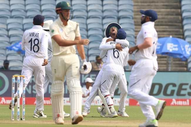 Teammates gather around Wriddhiman Saha after he plucks a blinder to dismiss Theunis de Bruyn.