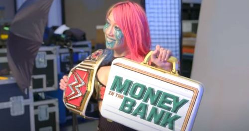 Asuka posing with the RAW Women's title and the MITB briefcase.