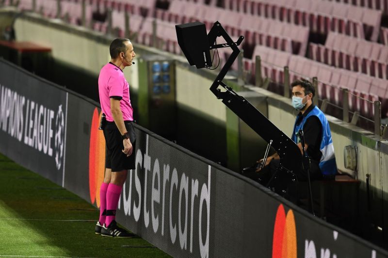 Referee Cuneyt Cakir watches carefully from the pitchside monitor during Barcelona's 3-1 win over Napoli