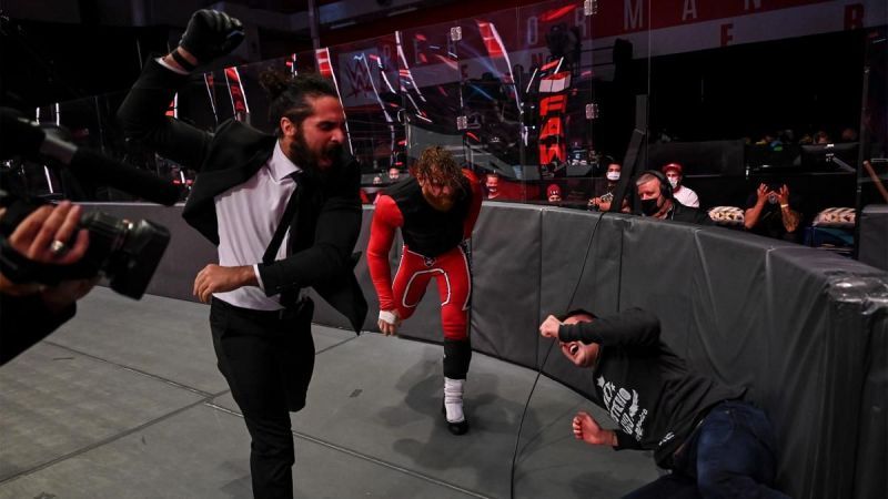 Seth Rollins and Murphy slamming Dominik Mysterio against the barricade