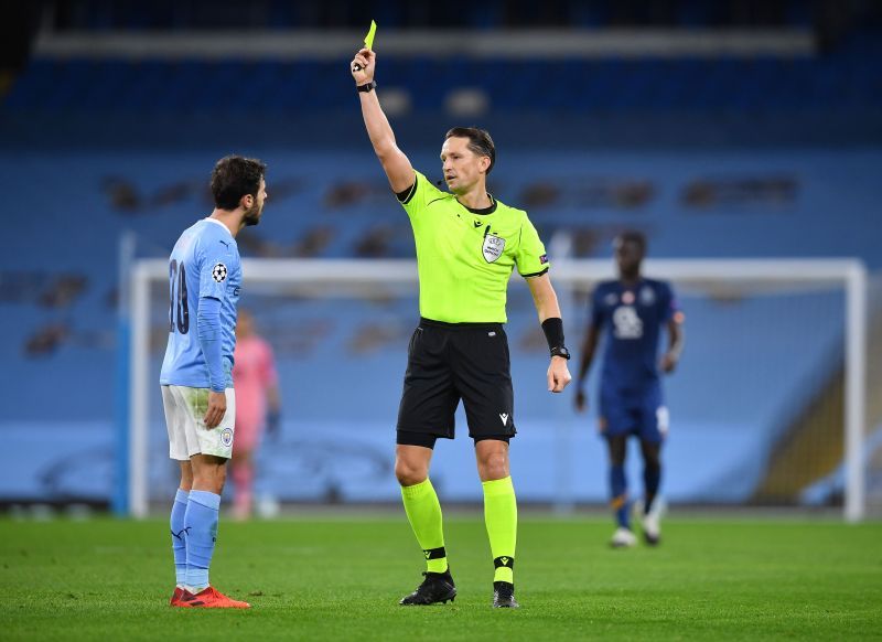 Match Referee Andris Treimanis shows a yellow card to Bernando Silva.