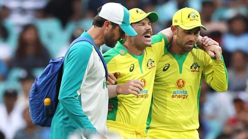 David Warner being helped off the field after sustaining a strain