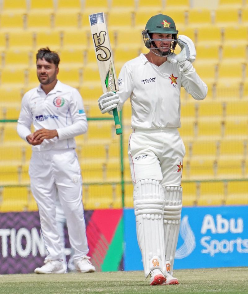 Sean Williams raises his bat after getting to 150 as Rashid Khan looks on.