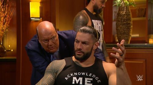 Roman Reigns and Paul Heyman converse in the backstage area