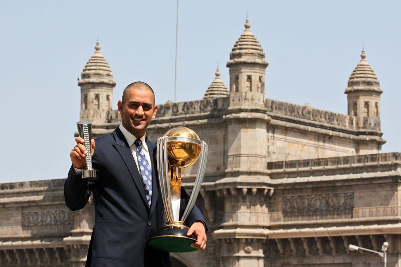 MS Dhoni poses with the 2011 World Cup and the Player of the Match trophy.