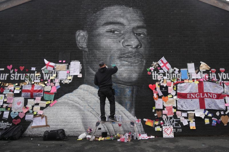Defaced mural of Marcus Rashford being repaired by the artist in Manchester
