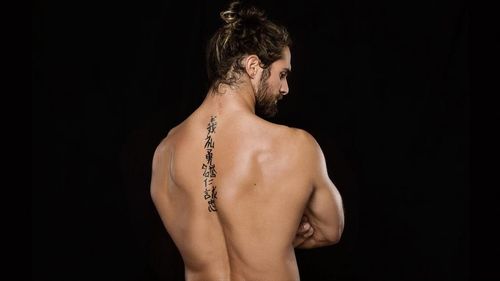 Seth Rollins showcasing his back tattoo