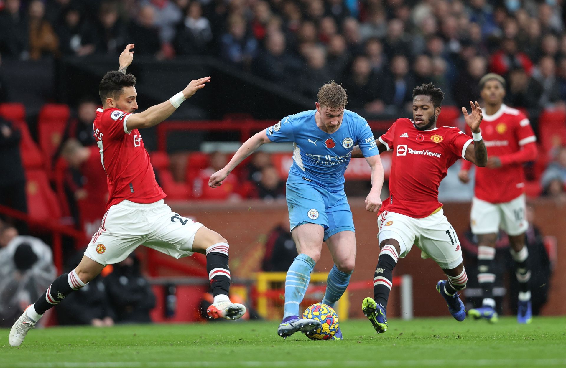 Kevin De Bruyne (C) skips past Bruno Fernandes (L) and Fred (R) of Manchester United