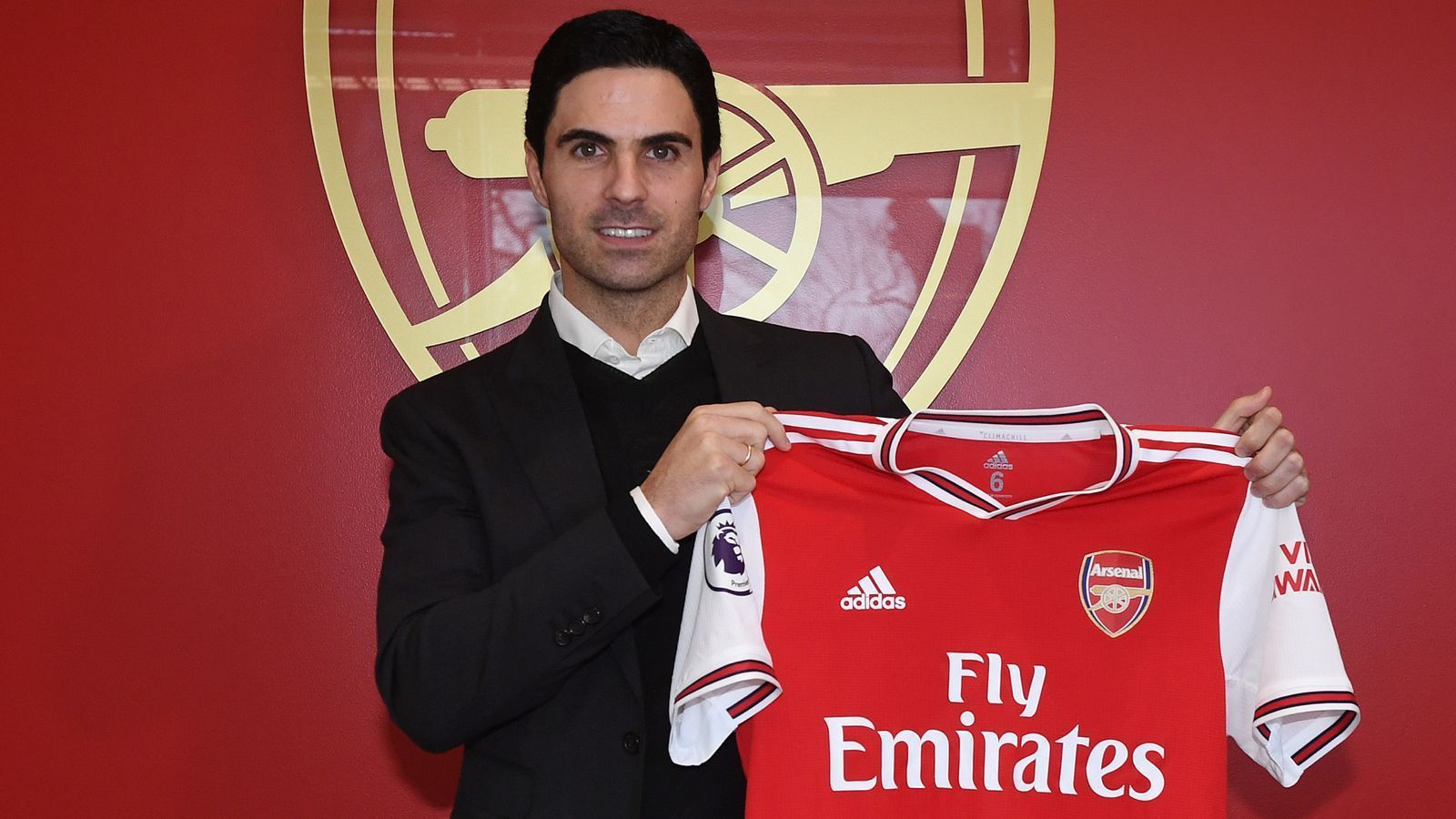 Mikel Arteta posing with the Arsenal jersey after being appointed as head coach in 2019.