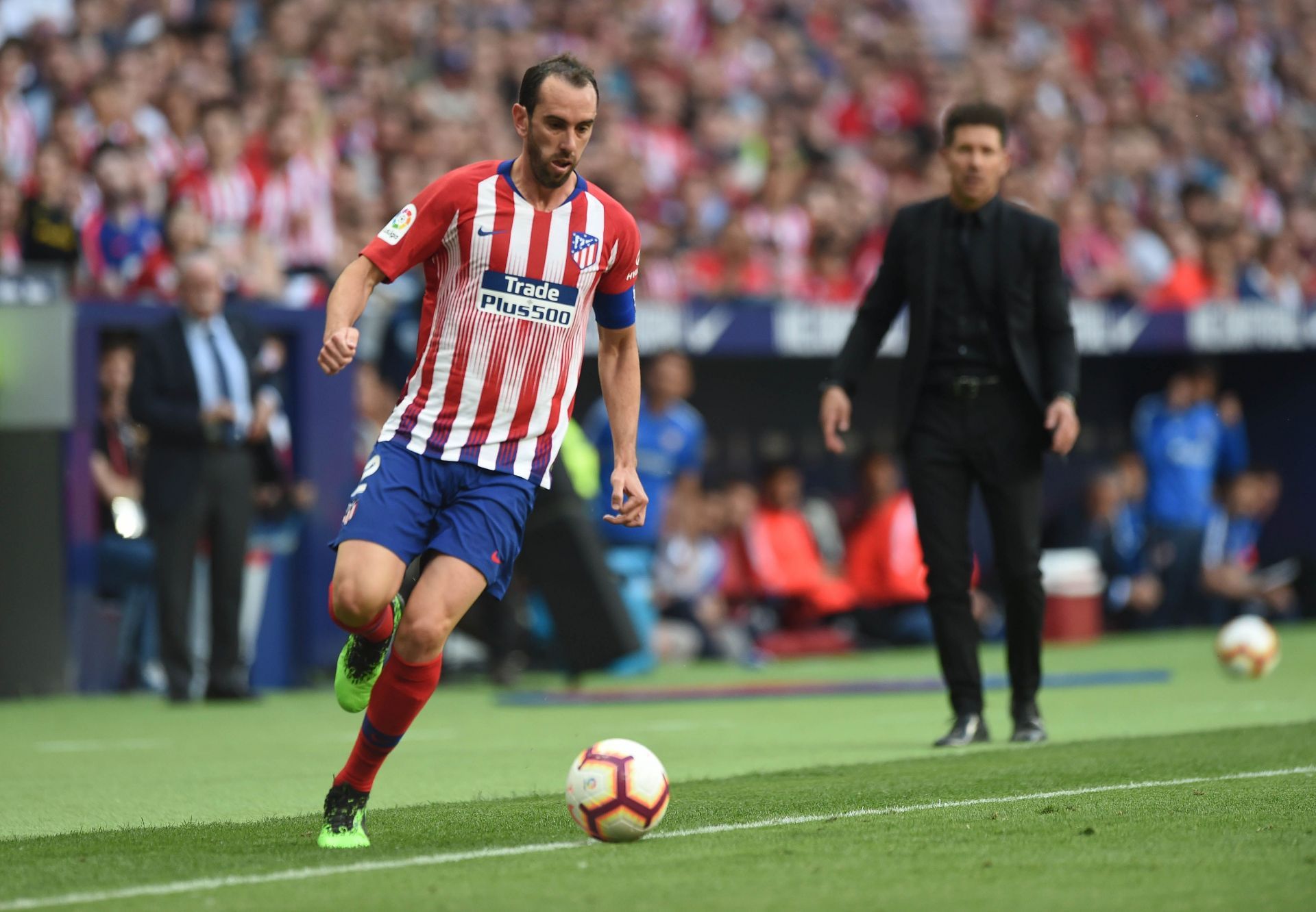 Diego Godin gets forward while Diego Simeone watches on.