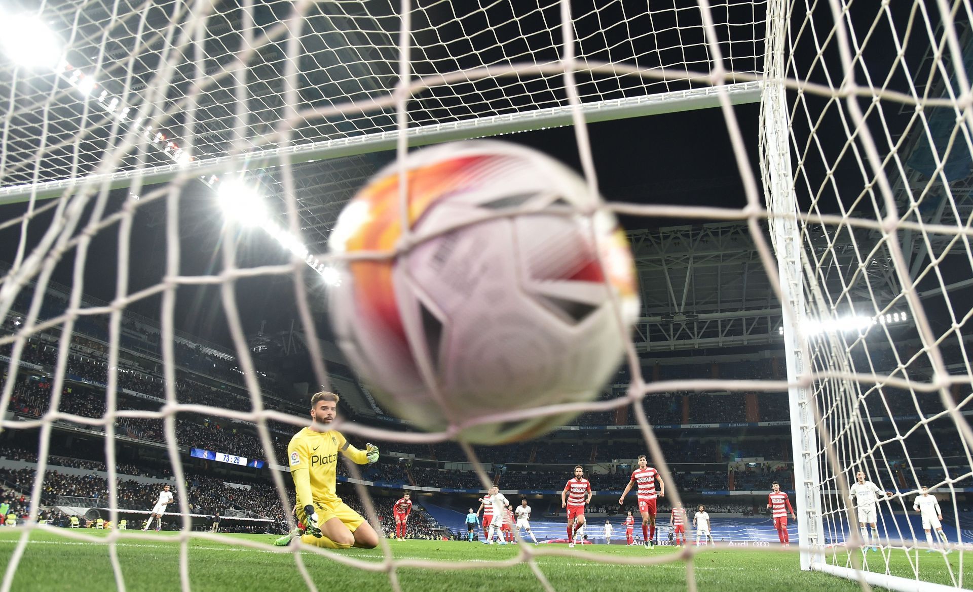 Granada goalkeeper Luis Maximiano watches helplessly as Marco Asensio&#039;s shot hits the back of the net for Real Madrid.