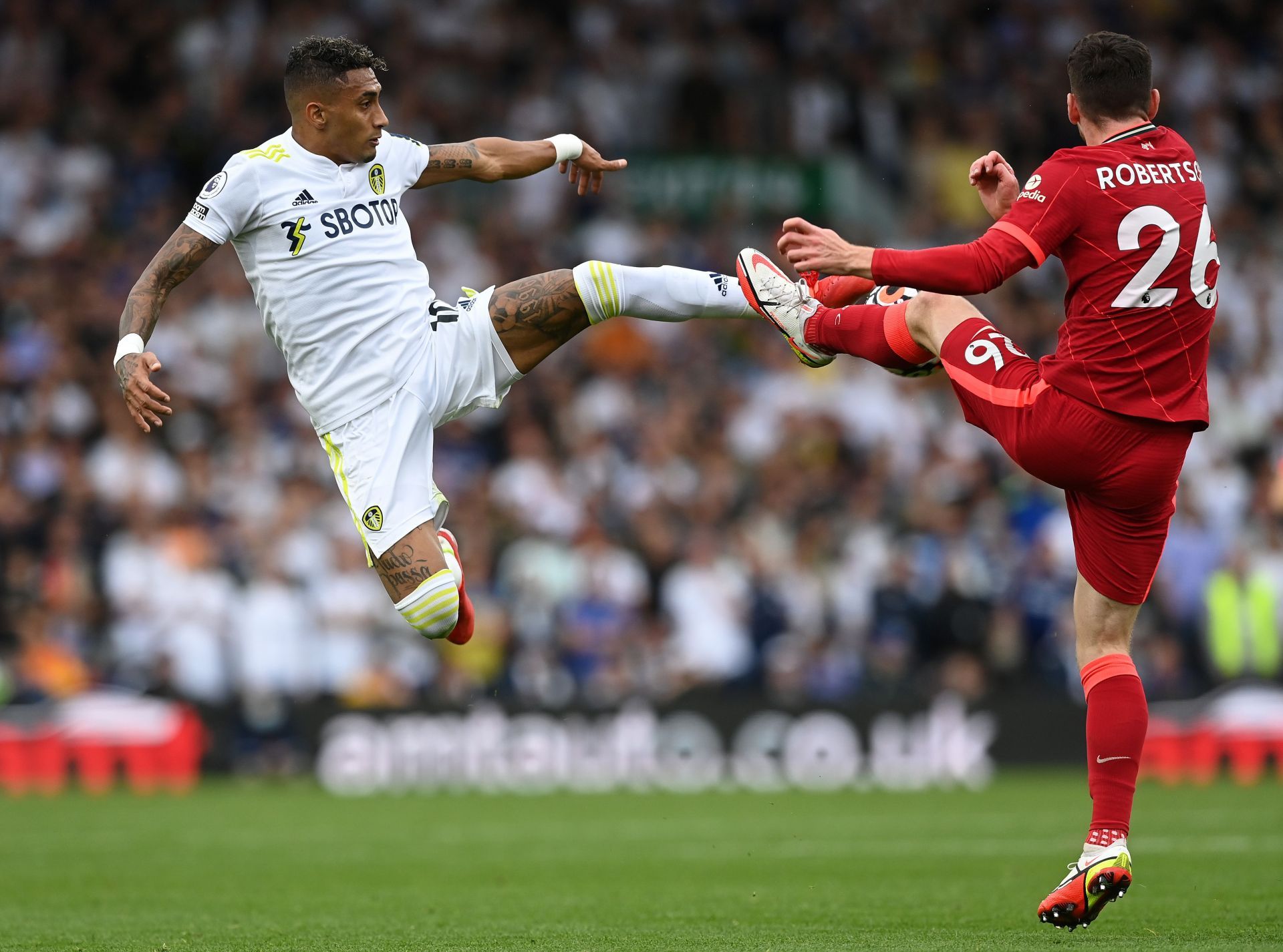 Liverpool's Andy Robertson (#26) challenges Raphinha (left)