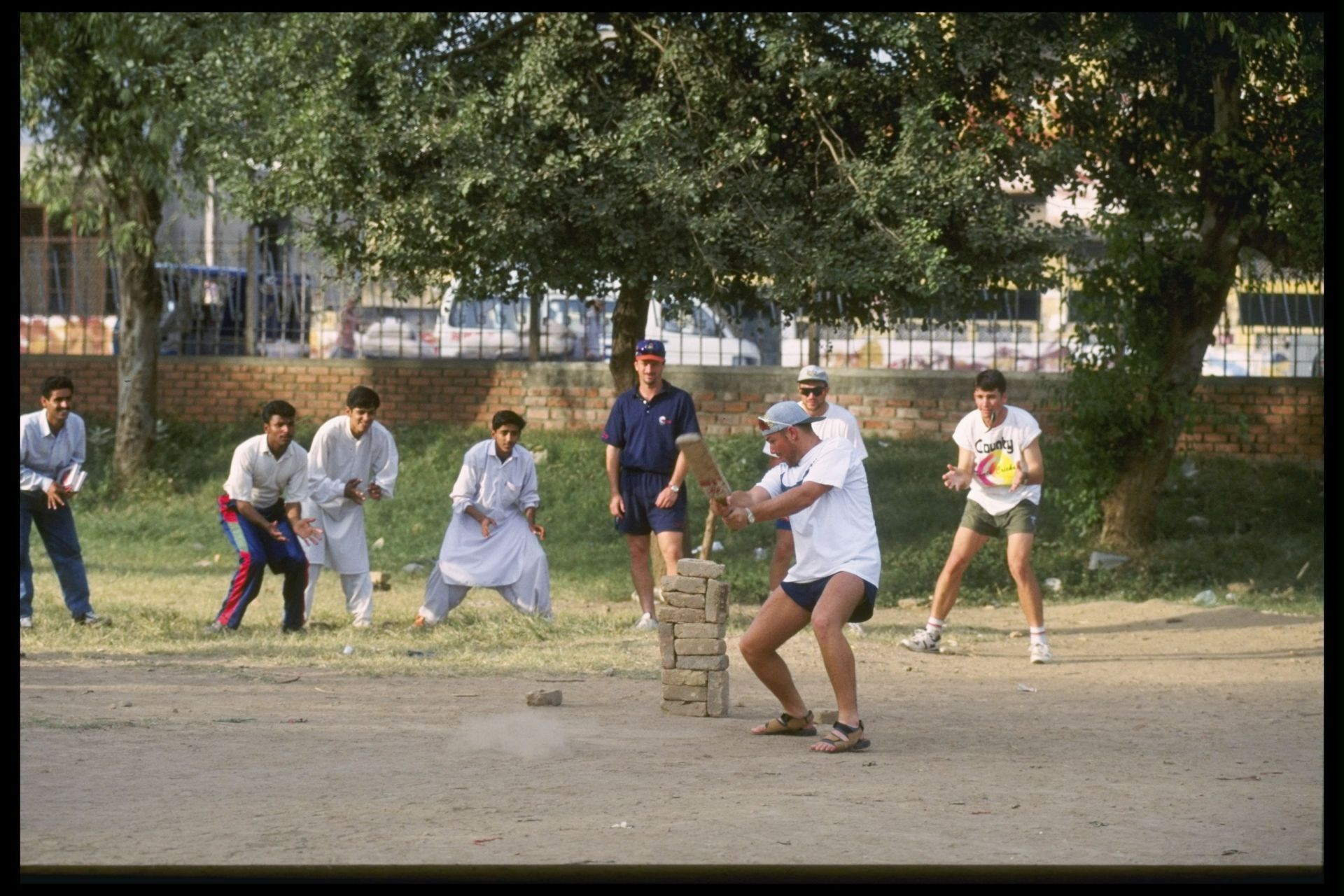 Shane Warne plays cricket with the locals during Australia's tour to Pakistan in 1994. Team-mates Mark Waugh, Michael Slater and Damien Fleming wait in the slips. Pic: Getty Images