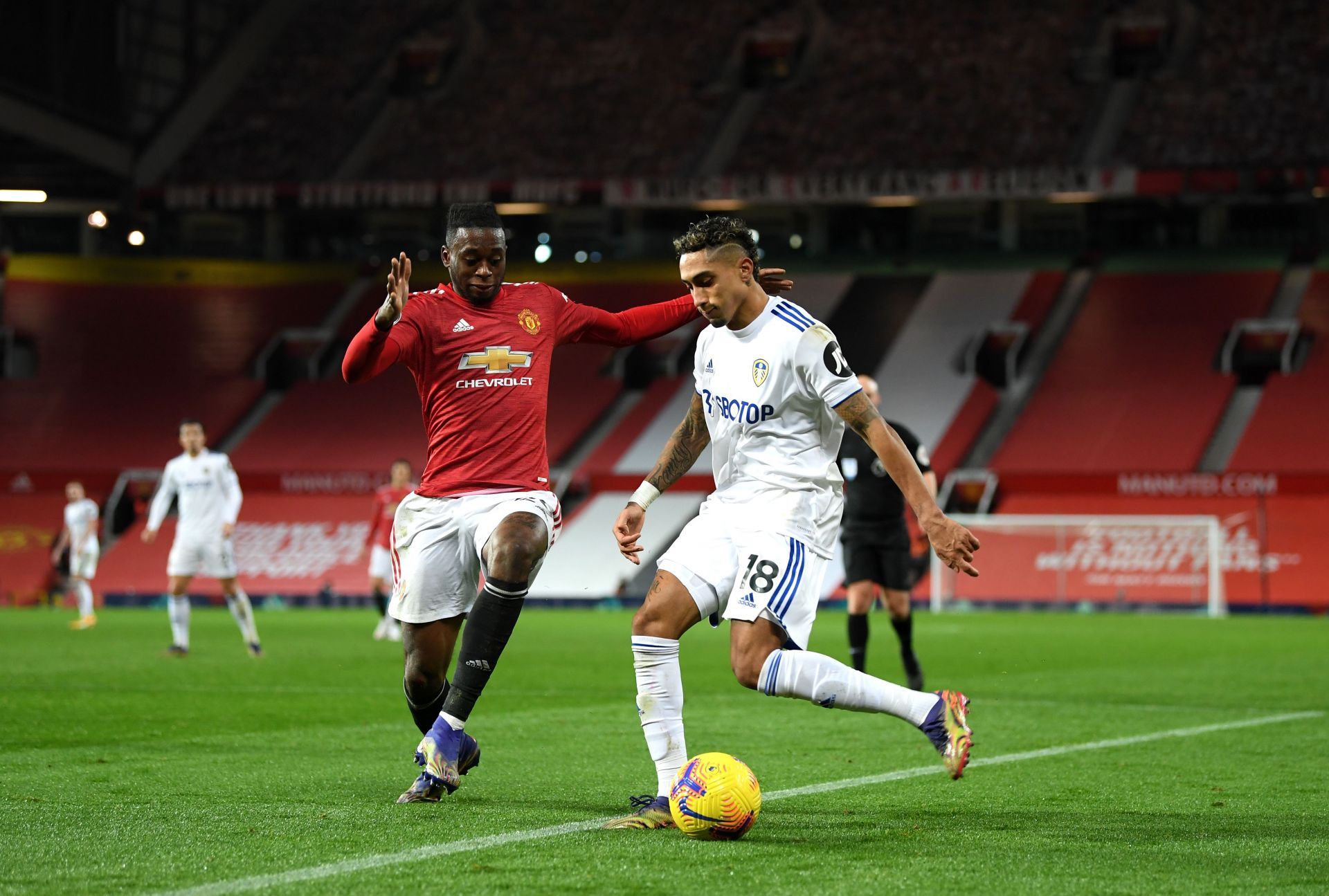 Aaron Wan-Bissaka (left) challenges Leeds' #18 in a Premier League game.