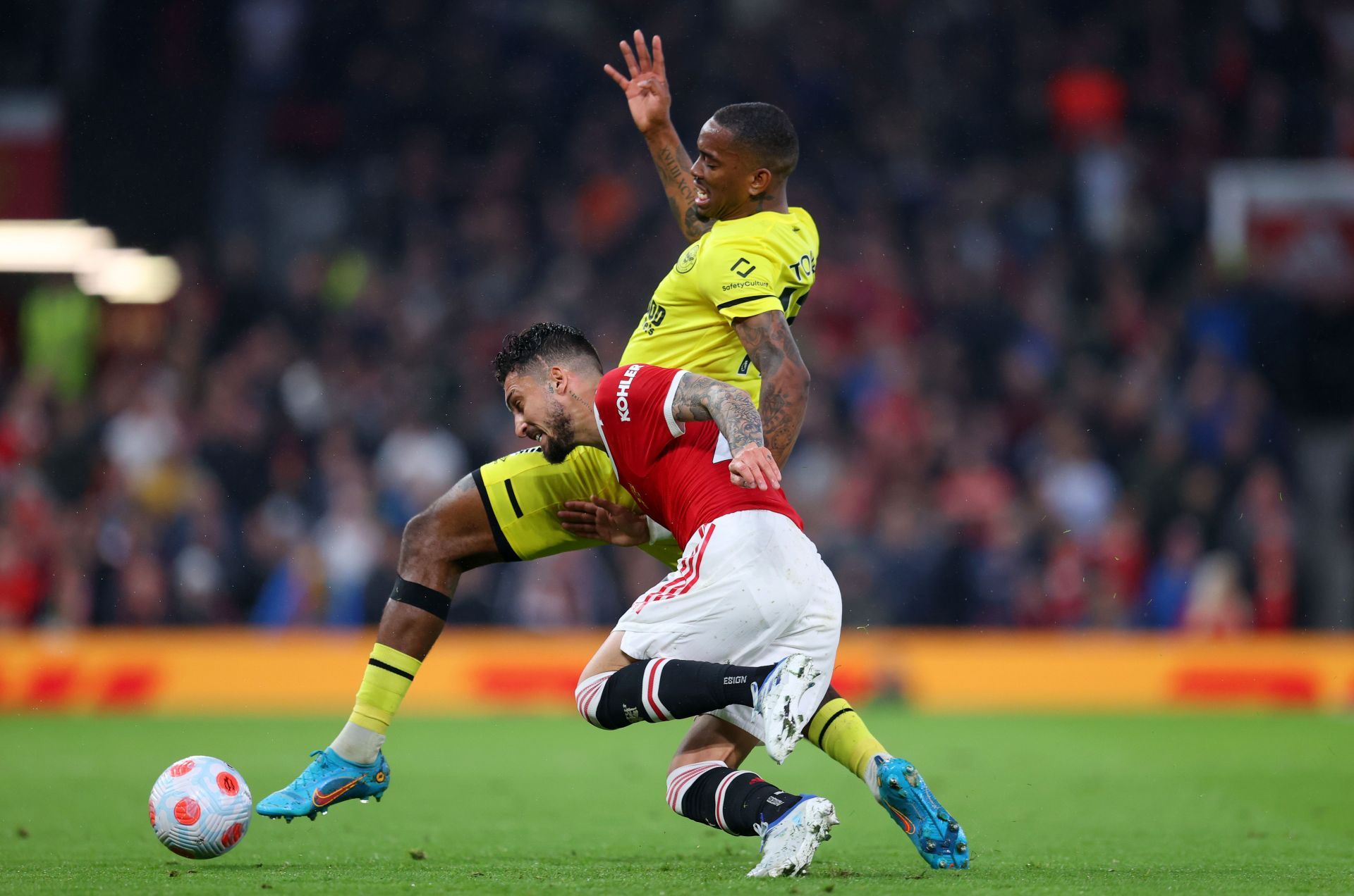 Brentford&#039;s Ivan Toney (in yellow) grapples with Manchester United&#039;s Alex Telles (in red)