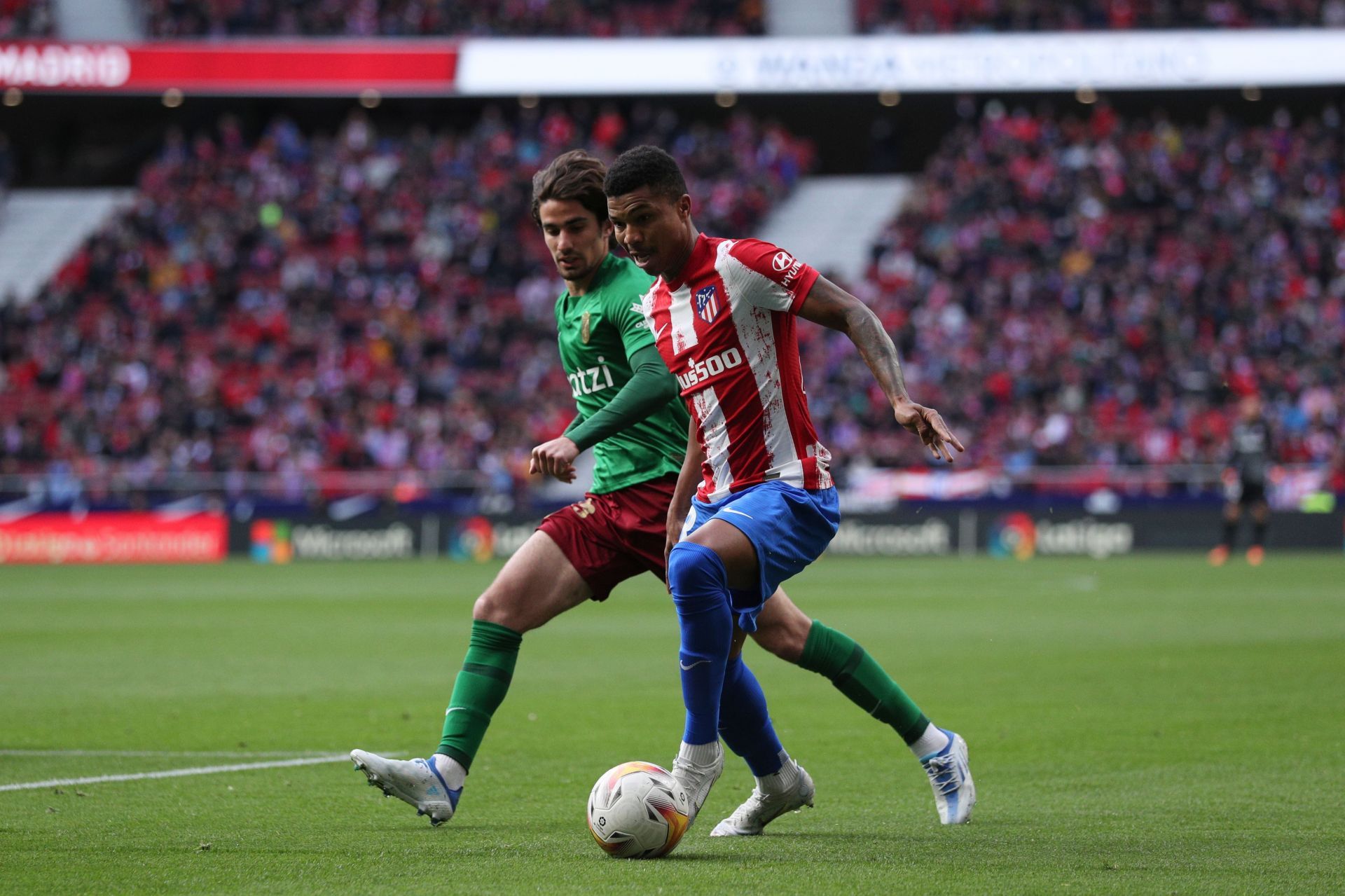 Alex Collado (left) of Granada battles for possession with Atletico Madrid's Reinildo Mandava (right)