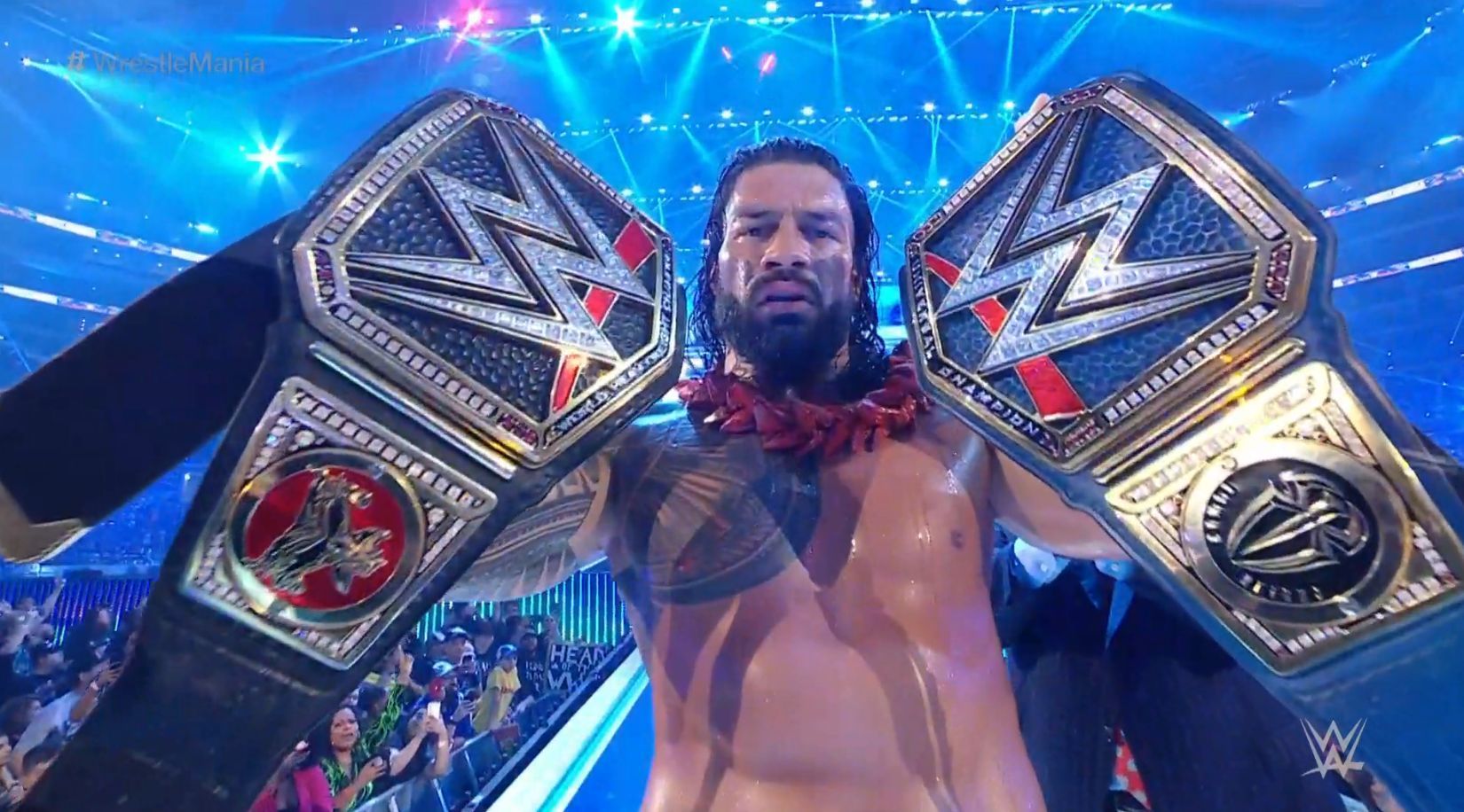 Roman Reigns posing with the Universal and WWE Championships