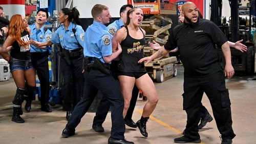 Ronda Rousey being placed under arrest during a wild brawl with Charlotte & Becky Lynch