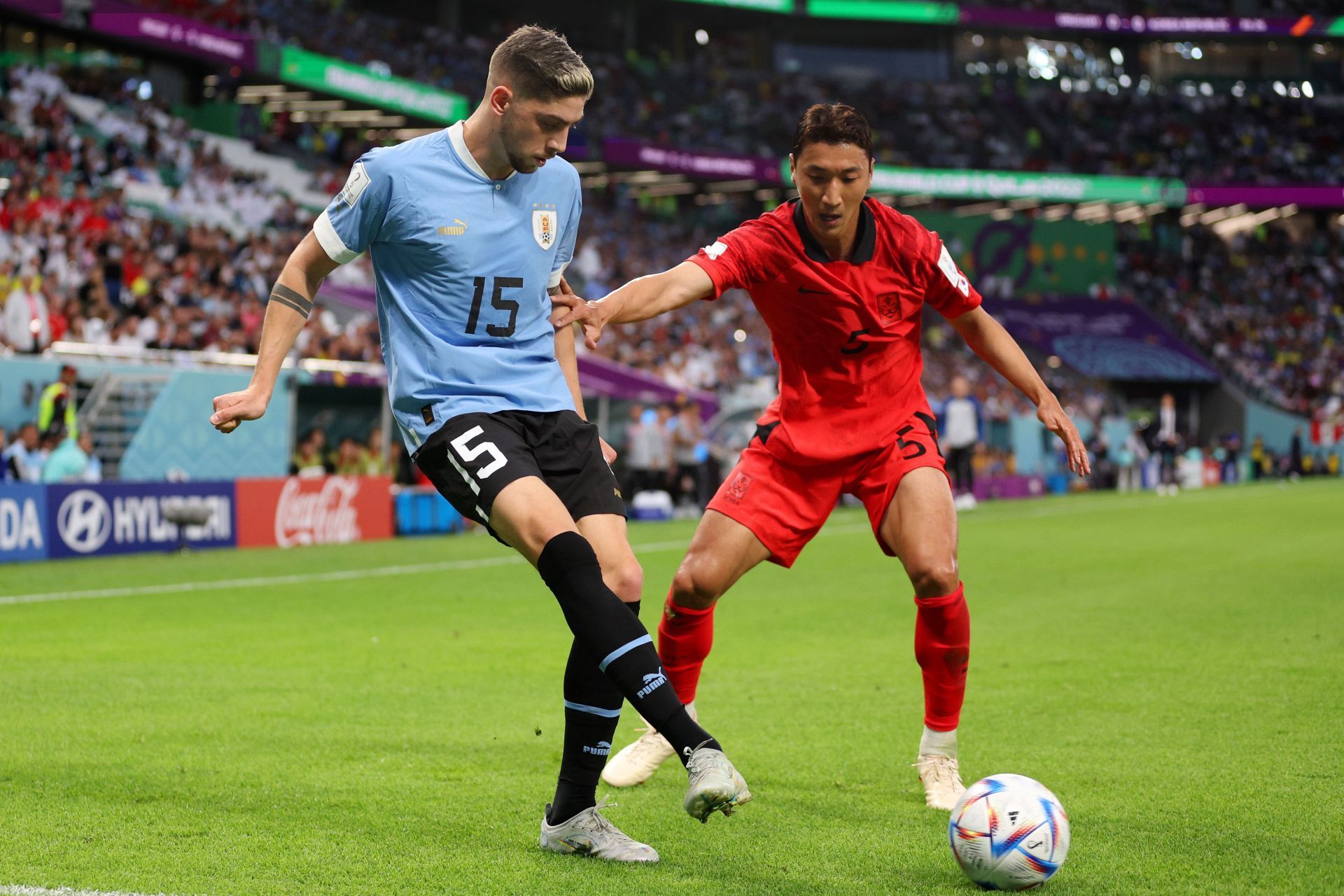 Federico Valverde passes the ball under pressure from Wooyoung Jung.
