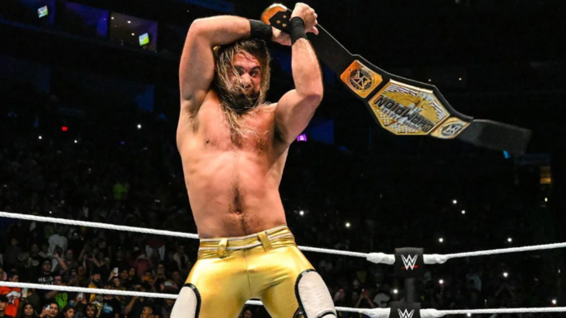 Seth Rollins celebrates after retaining the United States Championship at a WWE live event.