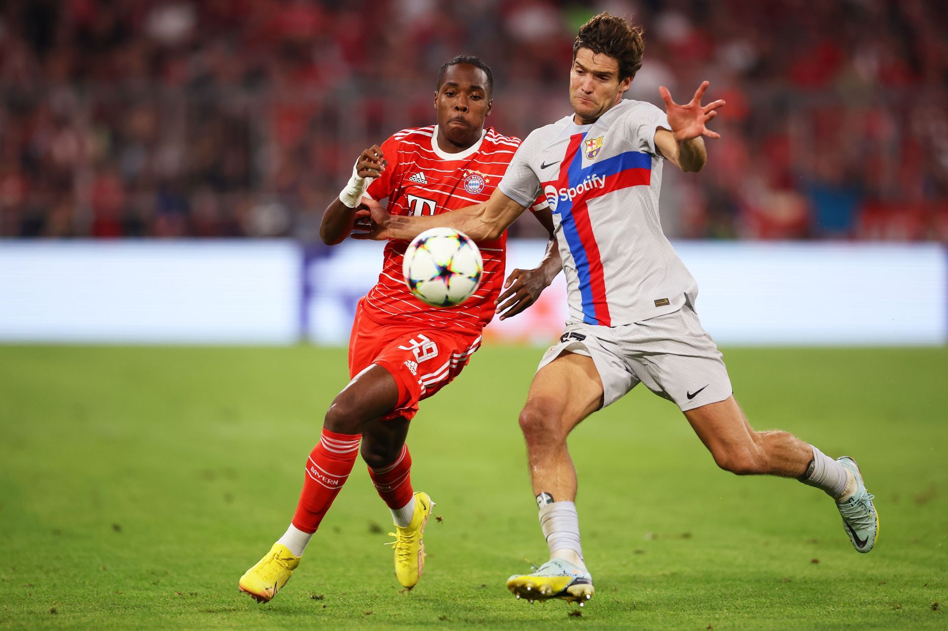 Mathys Tel and Marcos Alonso vie for the ball during Bayern Munich's Champions League match against FC Barcelona.