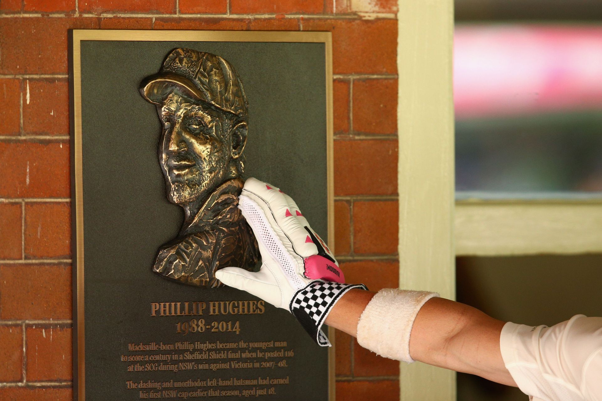 David Warner touches a bronze plaque tributing Phillip Hughes as he heads out to bat against India at the SCG