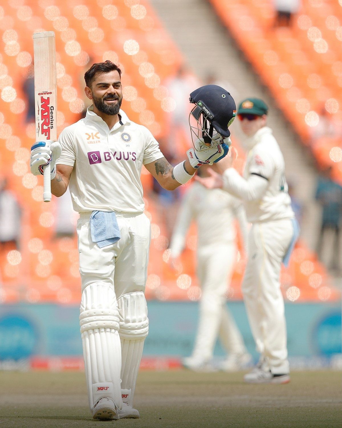 Virat Kohli celebrates his hundred, while Steve Smith claps in appreciation.