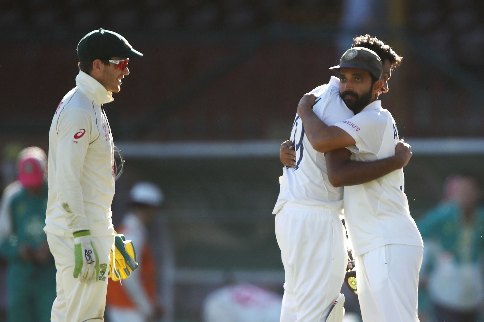 Tim Paine watches on as India captain Ajinkya Rahane embraces Ravichandran Ashwin after India managed to draw the Sydney Test