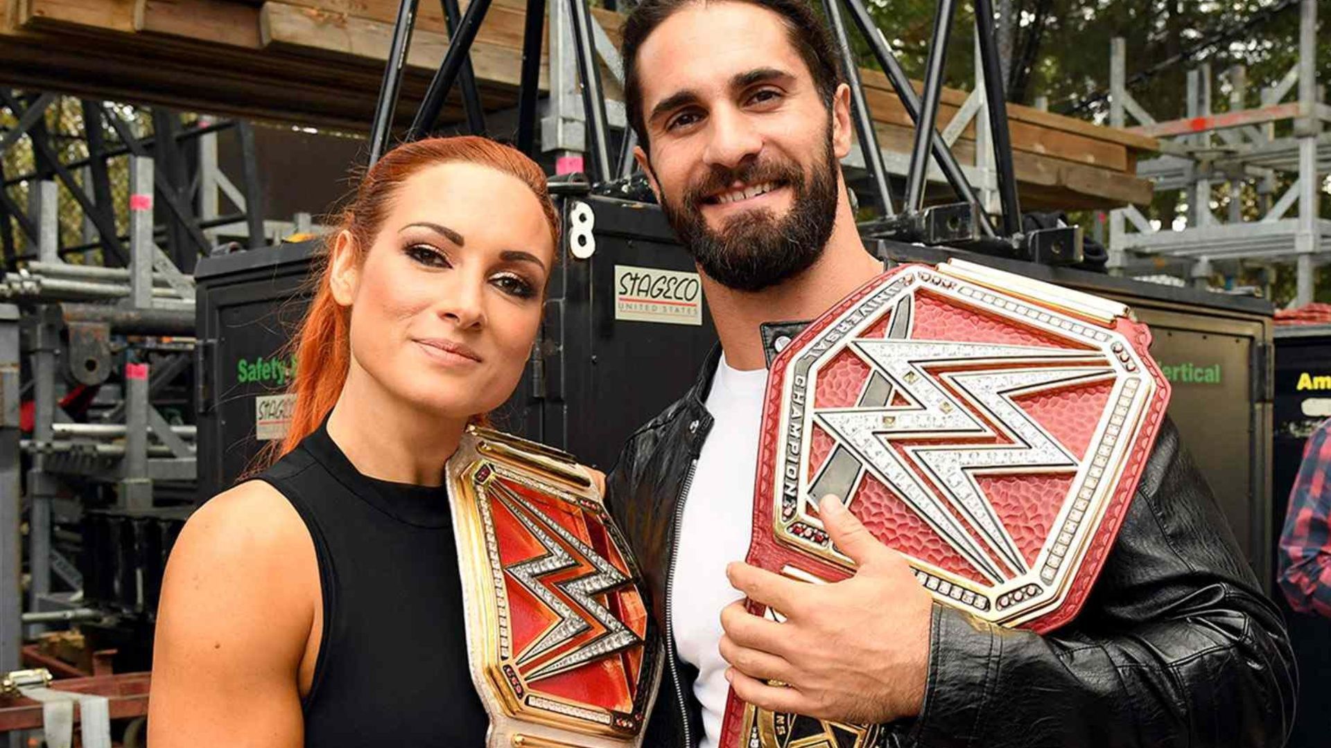 Becky Lynch and Seth Rollins pose for a snap with their titles.