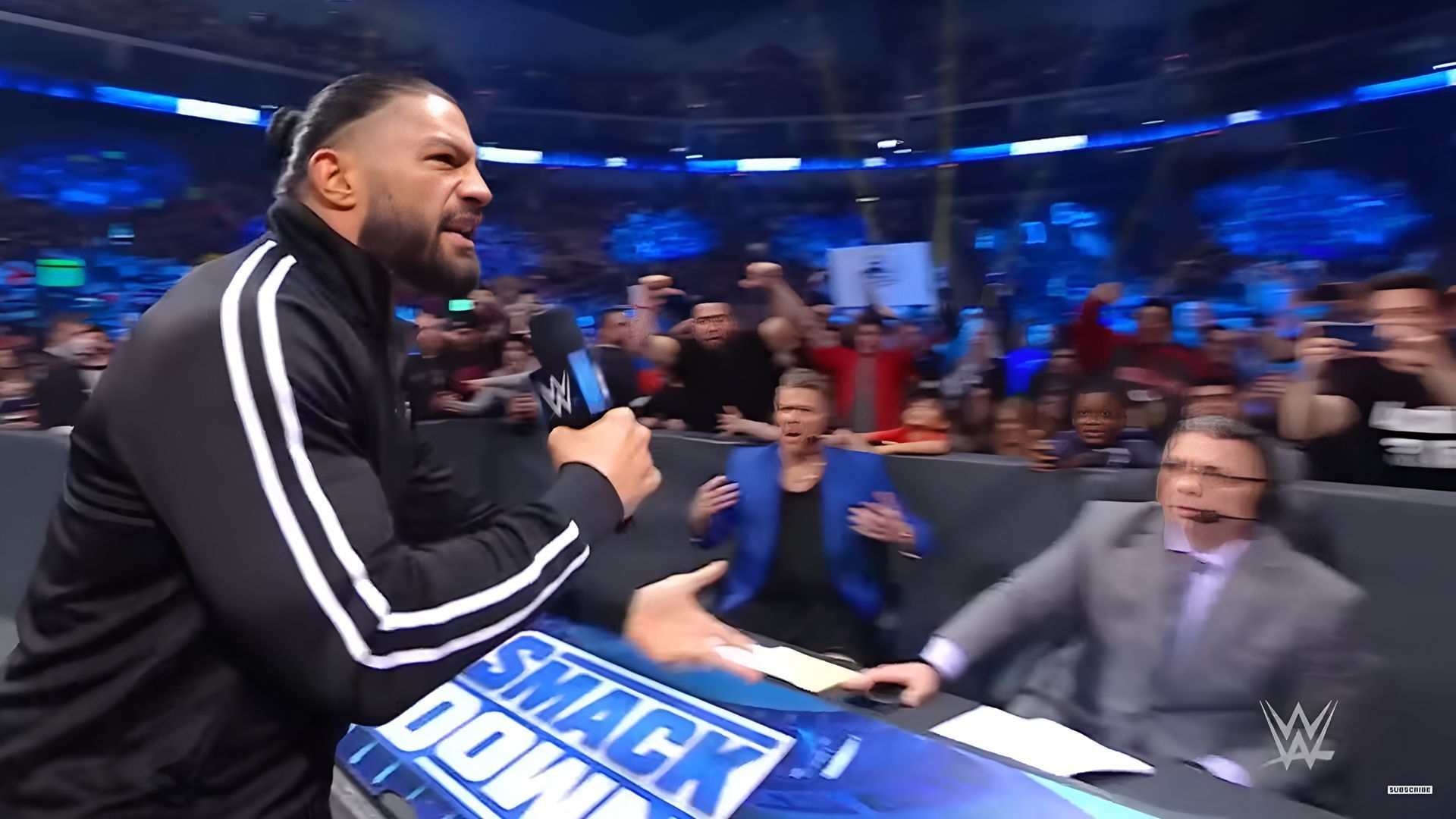 Roman Reigns pointing at the commentary team (via WWE