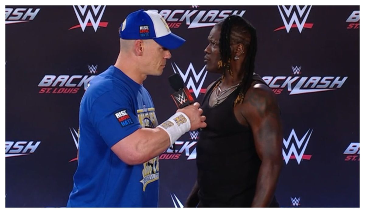 John Cena put R-Truth through the table at the Backlash Press Conference. (Image via WWE.com)