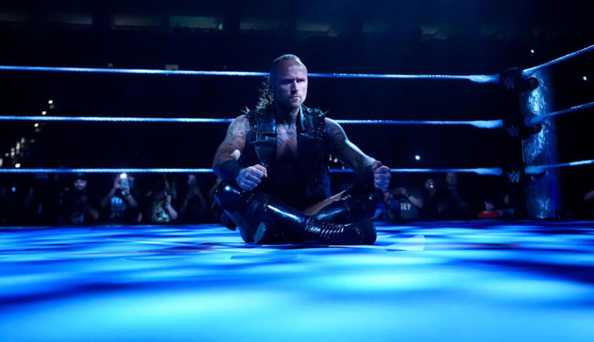 रिंग में बैठे हुए एलिस्टर ब्लैक (Photo: WWE.com)