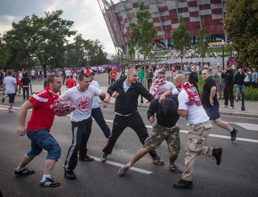 Polish football fans beat a Russian football fan during clashes in Warsaw on June 12