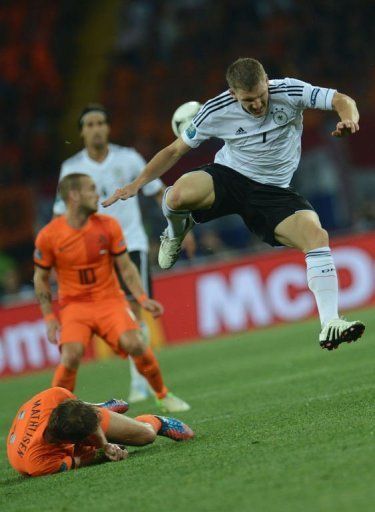 Dutch defender Joris Mathijsen (L) lays on the ground after vying with German midfielder Bastian Schweinsteiger